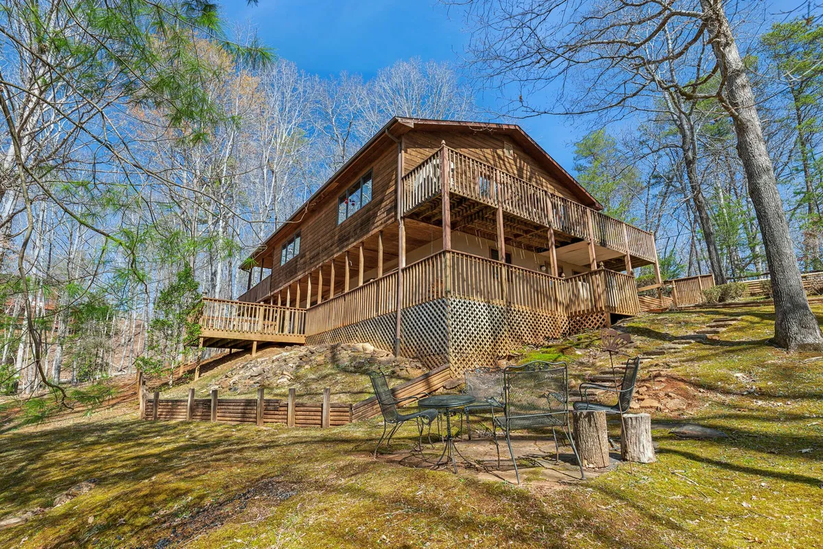 A tranquil image of the wooden house with surrounding trees and an outdoor seating area, inviting families to relax, dine al fresco, or unwind after a day of adventure. The deck and seating capture the spirit of outdoor living and shared moments.