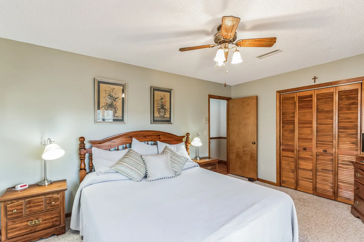 A tranquil bedroom featuring a bed with decorative pillows, framed artwork on the walls, and nightstands with warm lamps. Soft natural light filters through the window, creating a peaceful and inviting retreat, ideal for restful nights and quiet mornings.