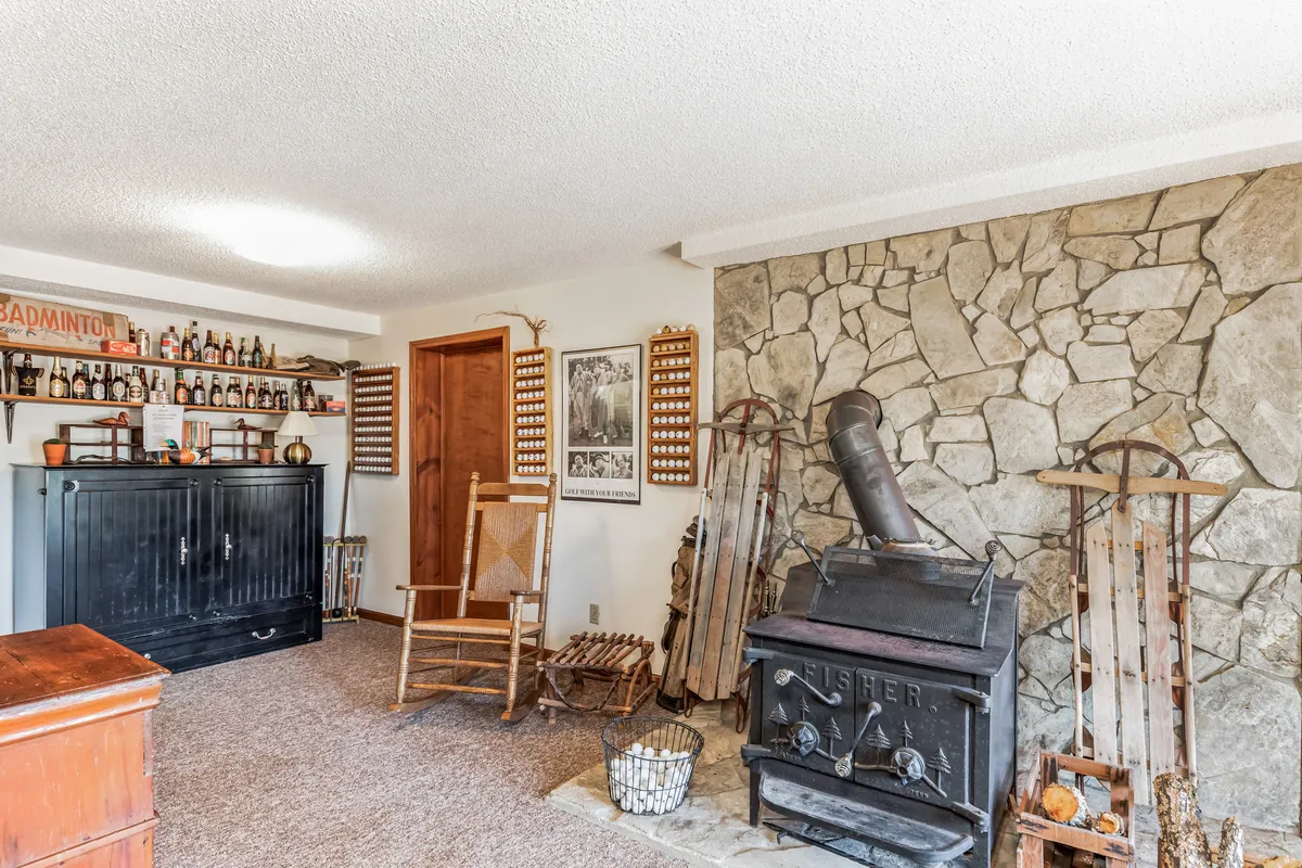 A rustic living area centered on a striking stone fireplace, with a wooden rocking chair and vintage decor. The scene exudes warmth and intimacy, inviting couples to enjoy cozy evenings or quiet reflection by the fire.