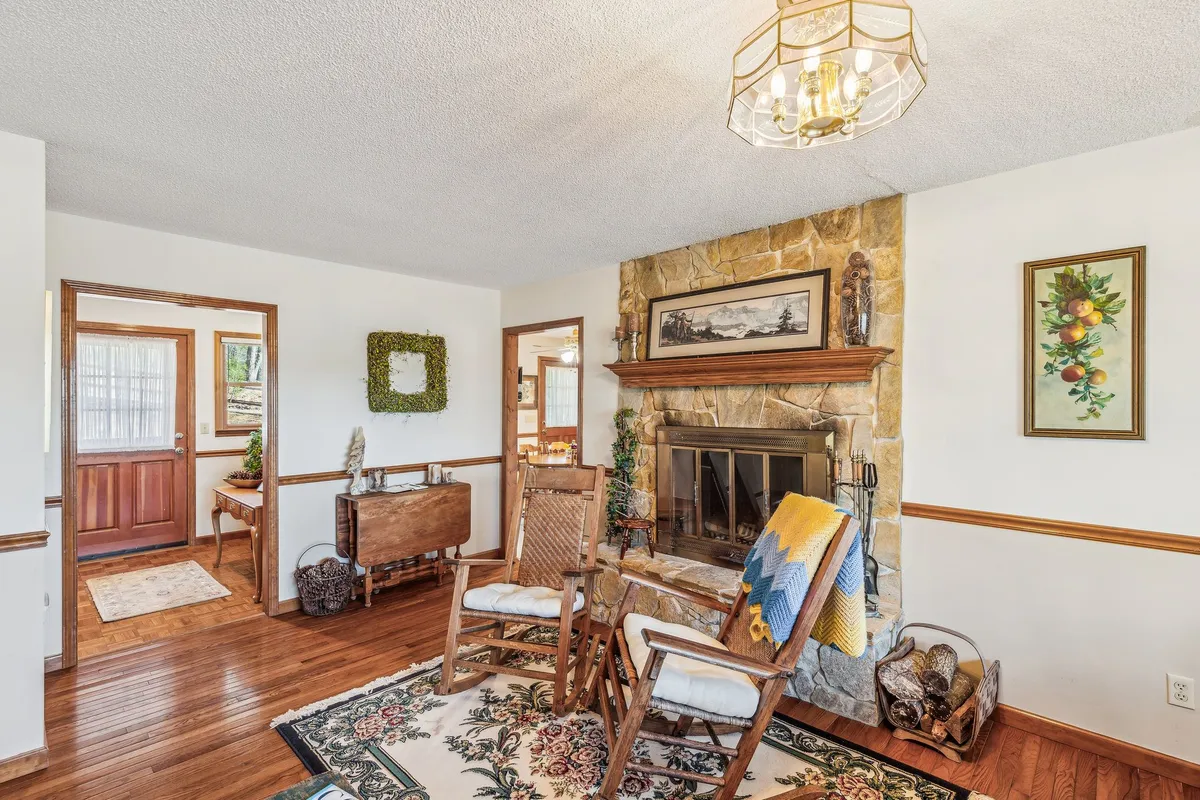 A warm, inviting living area with a rock fireplace, two cozy rocking chairs, a decorative rug, and wall art creates the quintessential communal gathering spot for relaxing evenings and group conversations.